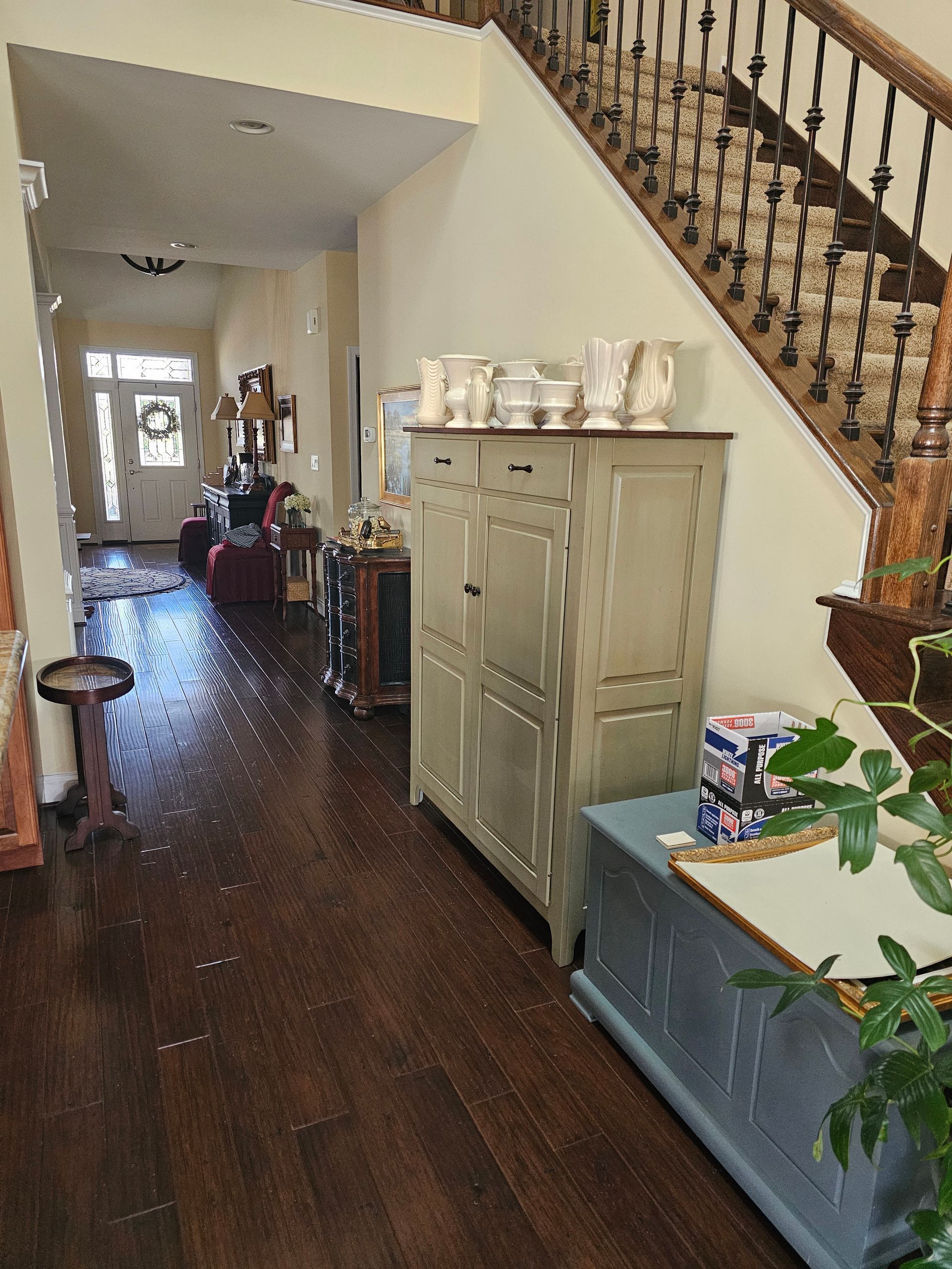 Room with burgundy wainscoting and tan walls. Paint supplies and tools are on the floor; window on the left.