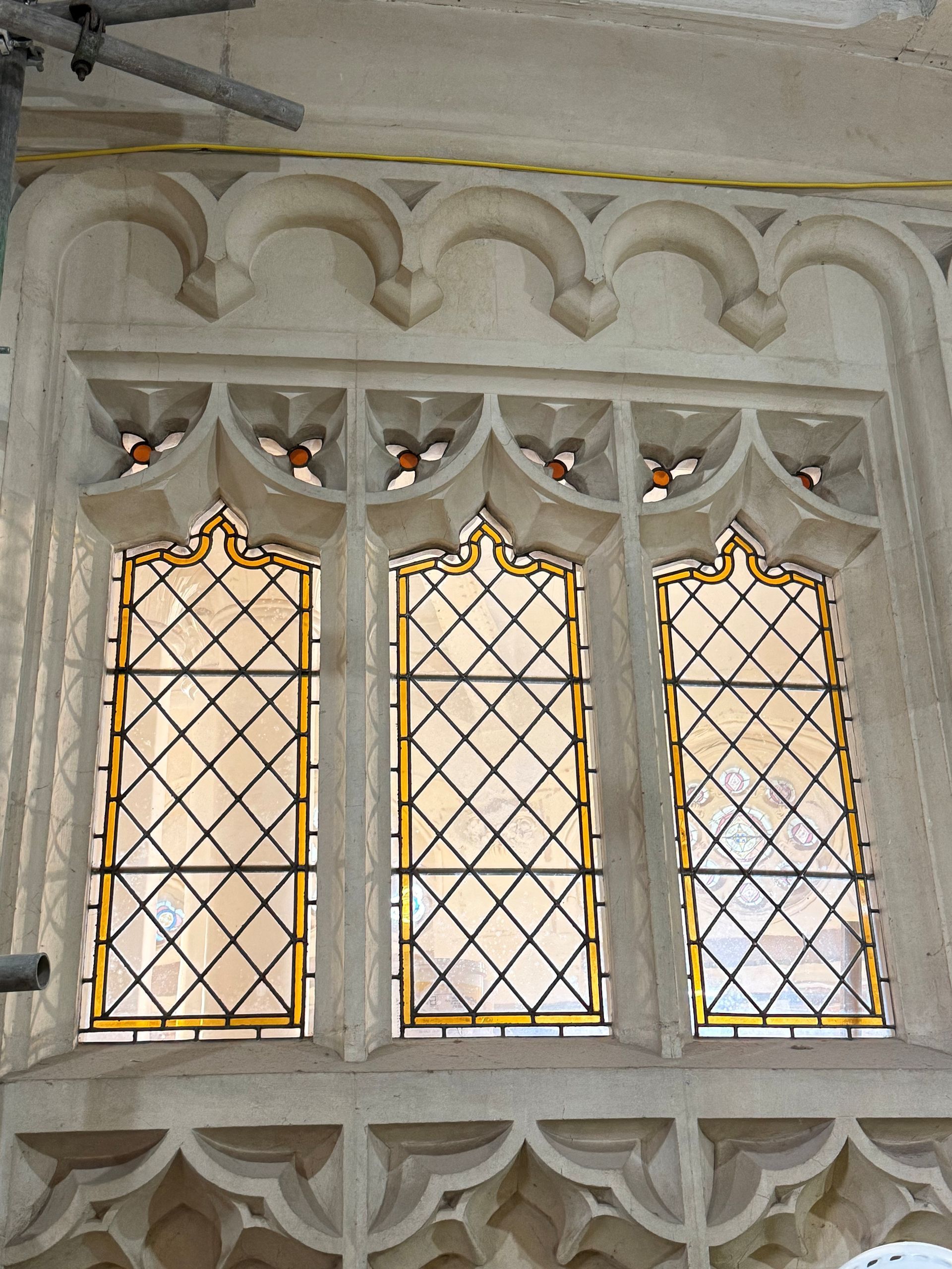 A triple-arched stone window with leaded diamond-pane glass and decorative stone tracery.