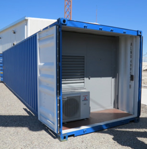 An open, blue shipping container on gravel contains a small air conditioning unit and a gray door.