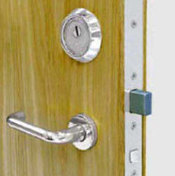 A close-up of a wooden door featuring a silver handle, a keyhole escutcheon, and an exposed metal locking mechanism.
