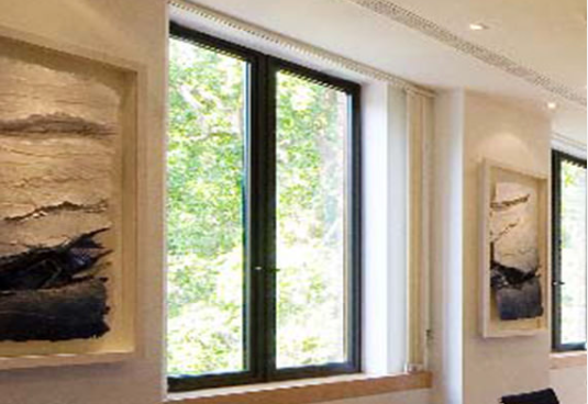 A bright room with a dark-framed window overlooking trees, flanked by two framed textured abstract art pieces.