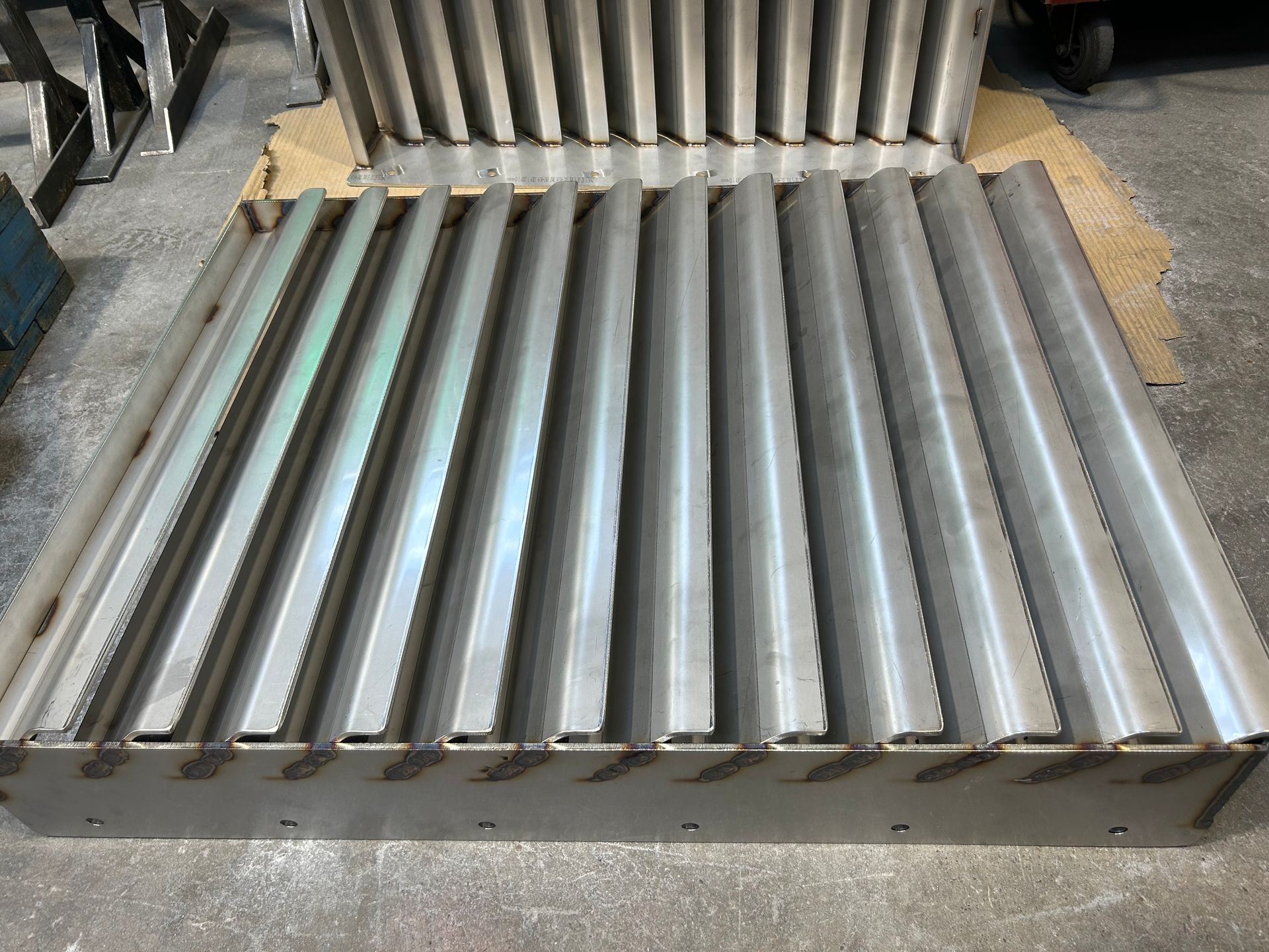 Two industrial stainless steel mist eliminator pads with parallel corrugated vanes resting on a shop floor.