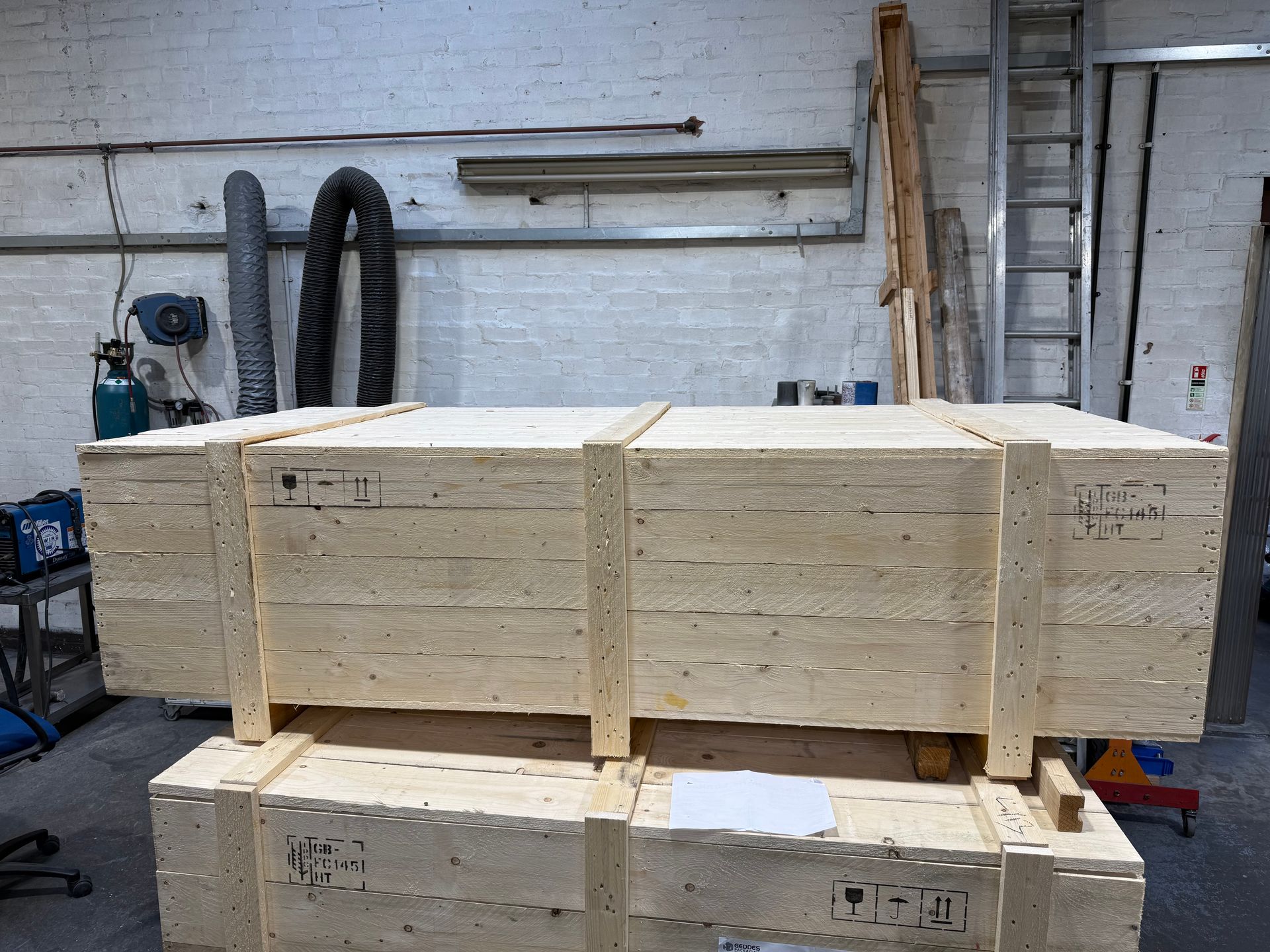 Two stacked, rectangular wooden shipping crates in a warehouse setting.