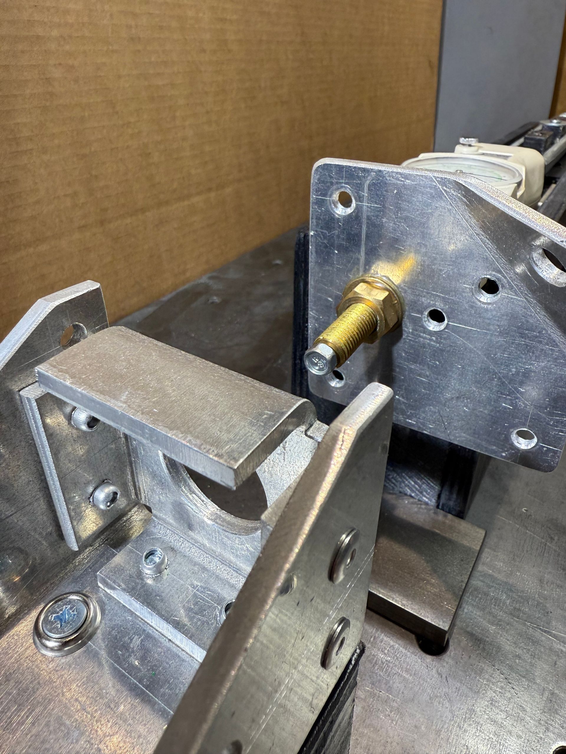 Close-up of industrial machinery components, featuring an aluminum bracket and a protruding brass threaded bolt.