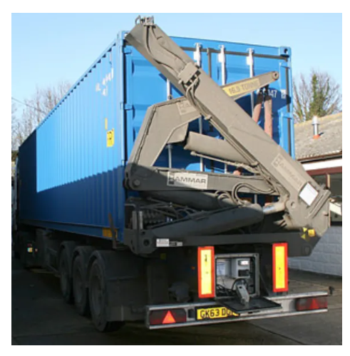 A side-view of a blue shipping container on a trailer, featuring a folded Hammar crane arm for self-loading.