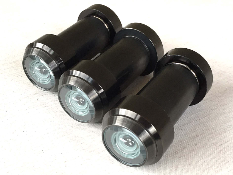 Three black door peepholes with glass lenses arranged diagonally on a white surface.