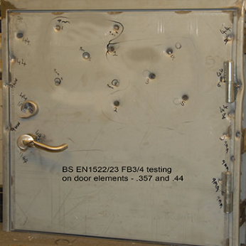 A steel door marked with bullet impacts and numbers, labeled