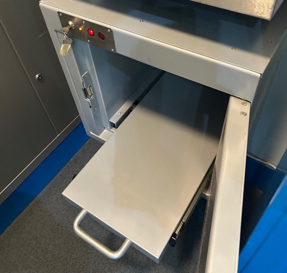 A gray metal equipment cabinet with an open pull-out drawer and a keyed lock panel on the front.