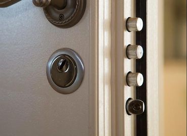 A close-up of a secure door lock system with a keyhole, a handle, and four extended steel locking bolts.