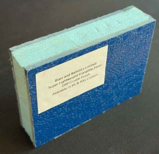 A sample of a blue, textured GRP frangible panel with a light green foam core and an attached product information label.