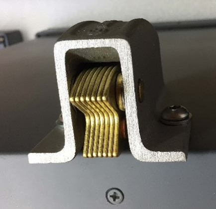 A close-up view of a metal cabinet door latch mechanism with vertical brass-colored spring plates inside a dark housing.