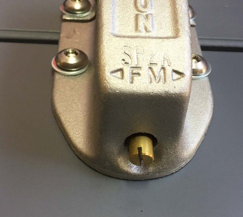 A metallic, bolted door latch with a brass slotted screw in the center and