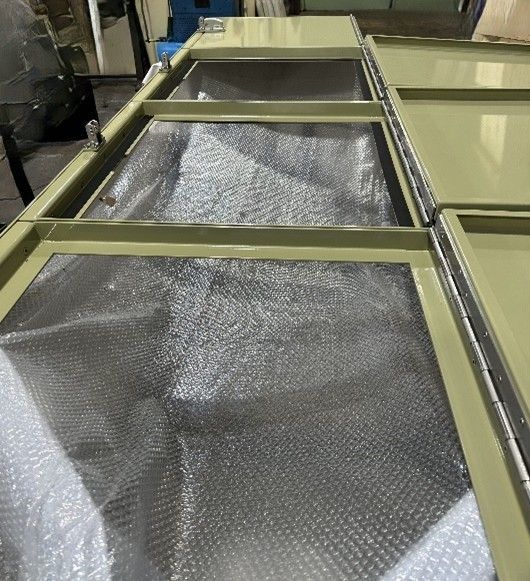 Tan metal frames holding bubble wrap, showing the interior of several open industrial storage compartments.