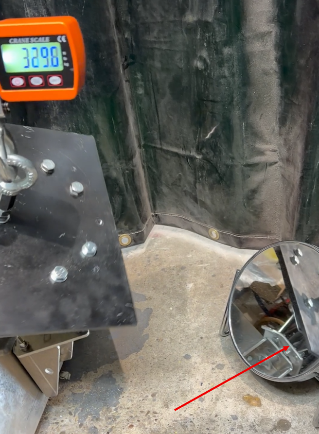 A crane scale shows 329.8 next to a metal component on the floor with a red arrow pointing to a bolted joint.