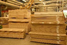 Several stacks of light-colored wooden boards stored in an industrial warehouse facility.