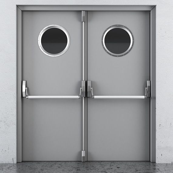 Double grey metal industrial doors with circular windows and horizontal push-bar panic handles.