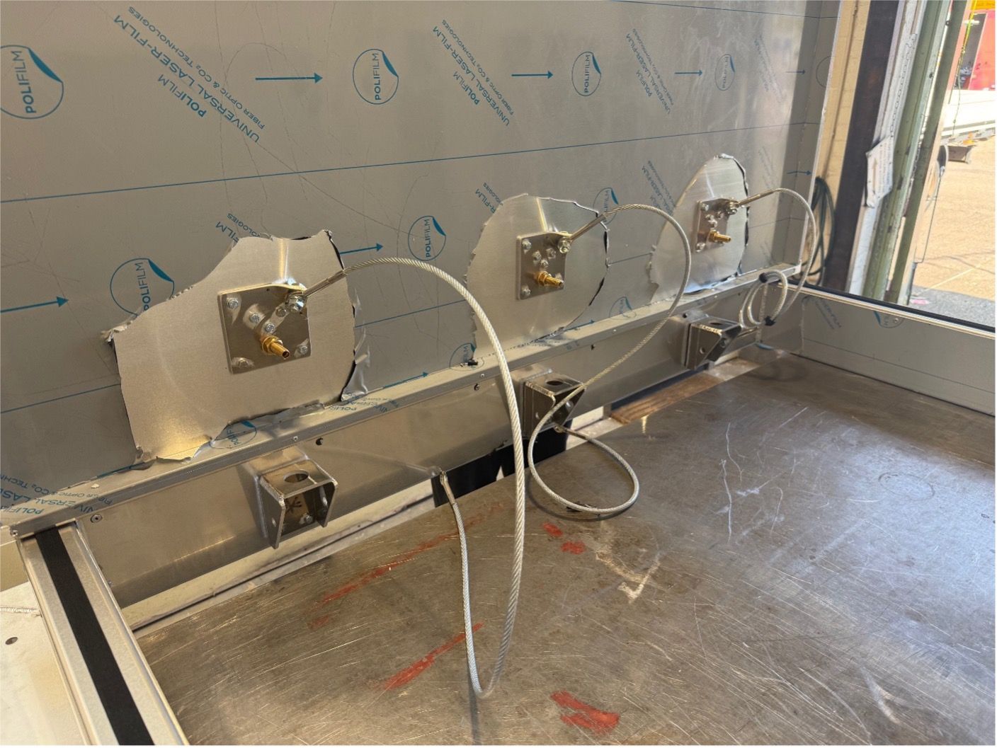 Three sensor modules mounted on a metal wall with wires connected, set in an industrial laboratory or workspace.