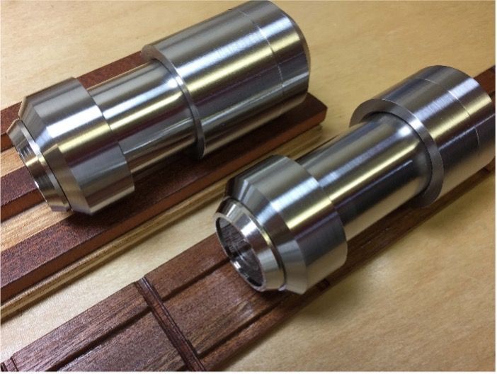 Two polished steel cylindrical machine parts resting on wooden slats.