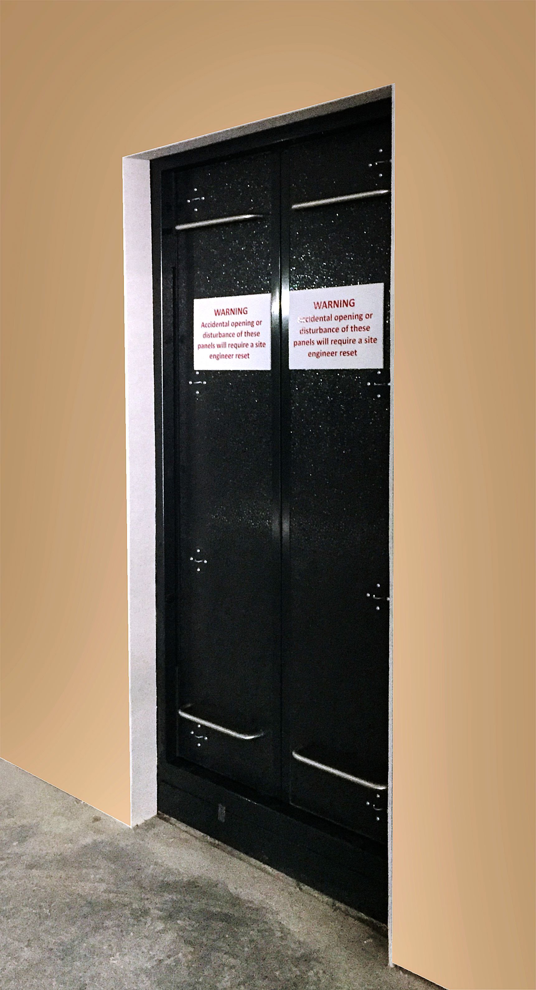 A black, double-door elevator entrance with two white signs attached to the center on a plain beige wall.
