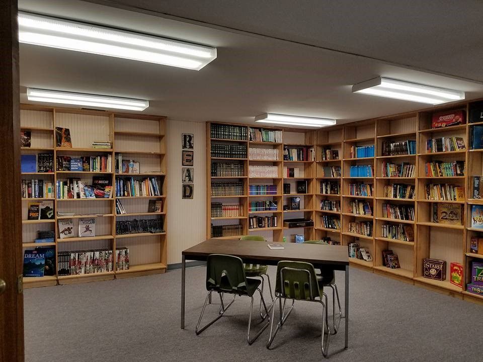 Library with bookshelves filled with books, a table, and chairs.
