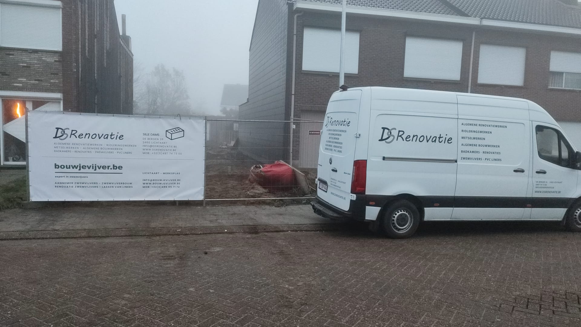 Voor een bakstenen gebouw staat een wit busje geparkeerd.