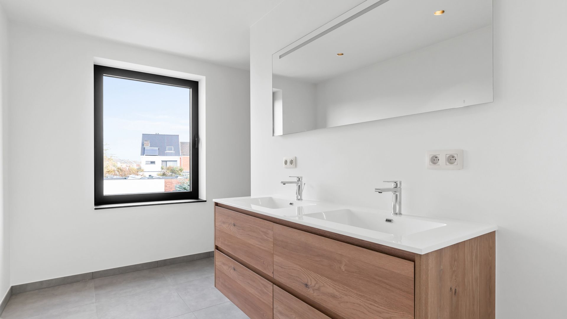 Een badkamer met twee wastafels, een spiegel en een raam.