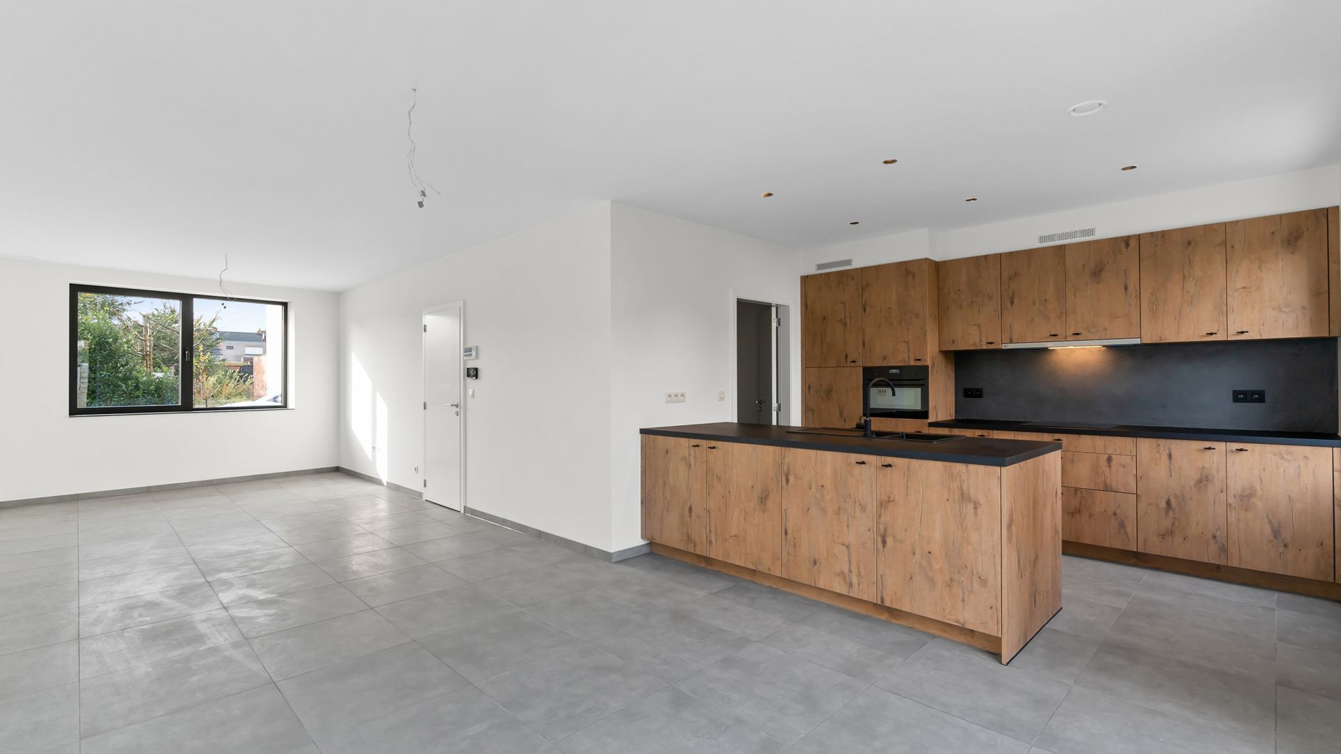 Een lege keuken met houten kasten en een groot eiland.