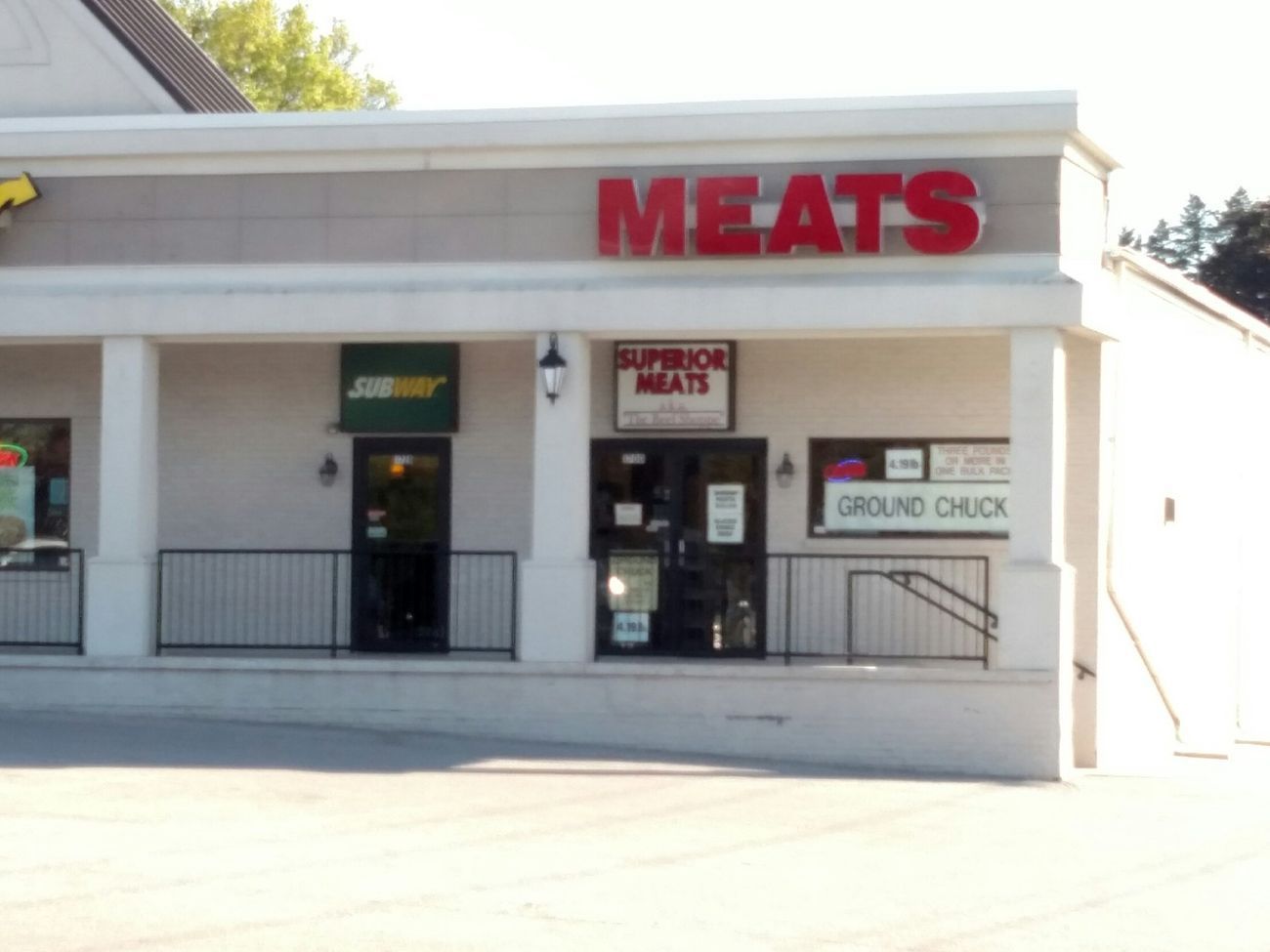Meat market storefront with red “MEATS” sign and entrance under a covered awning