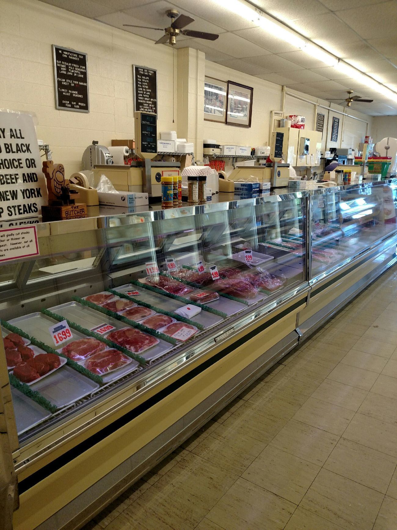 Butcher shop display case with rows of meat and deli items in a bright store interior