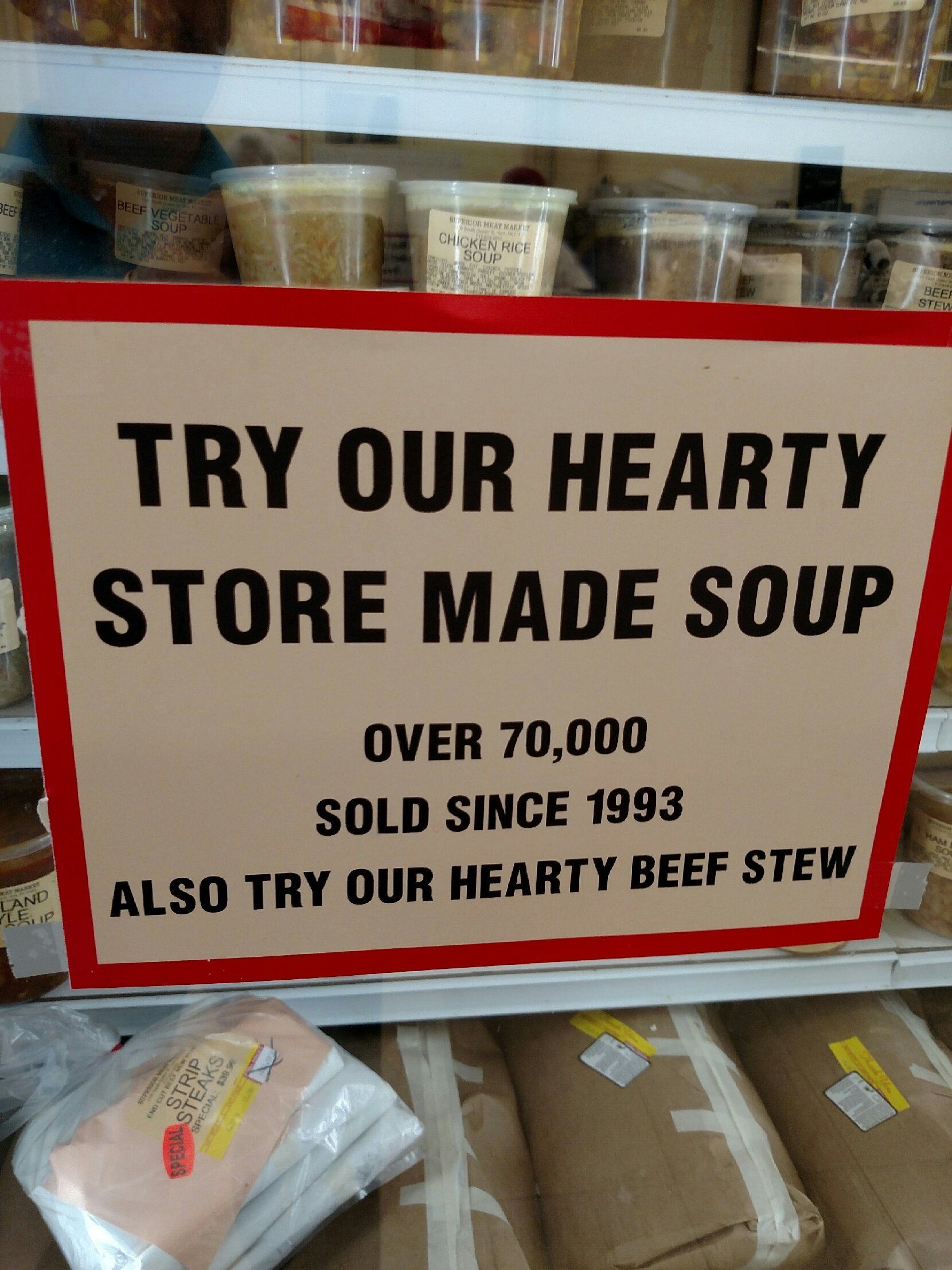 Sign for store-made soup and beef stew in front of shelves of packaged food
