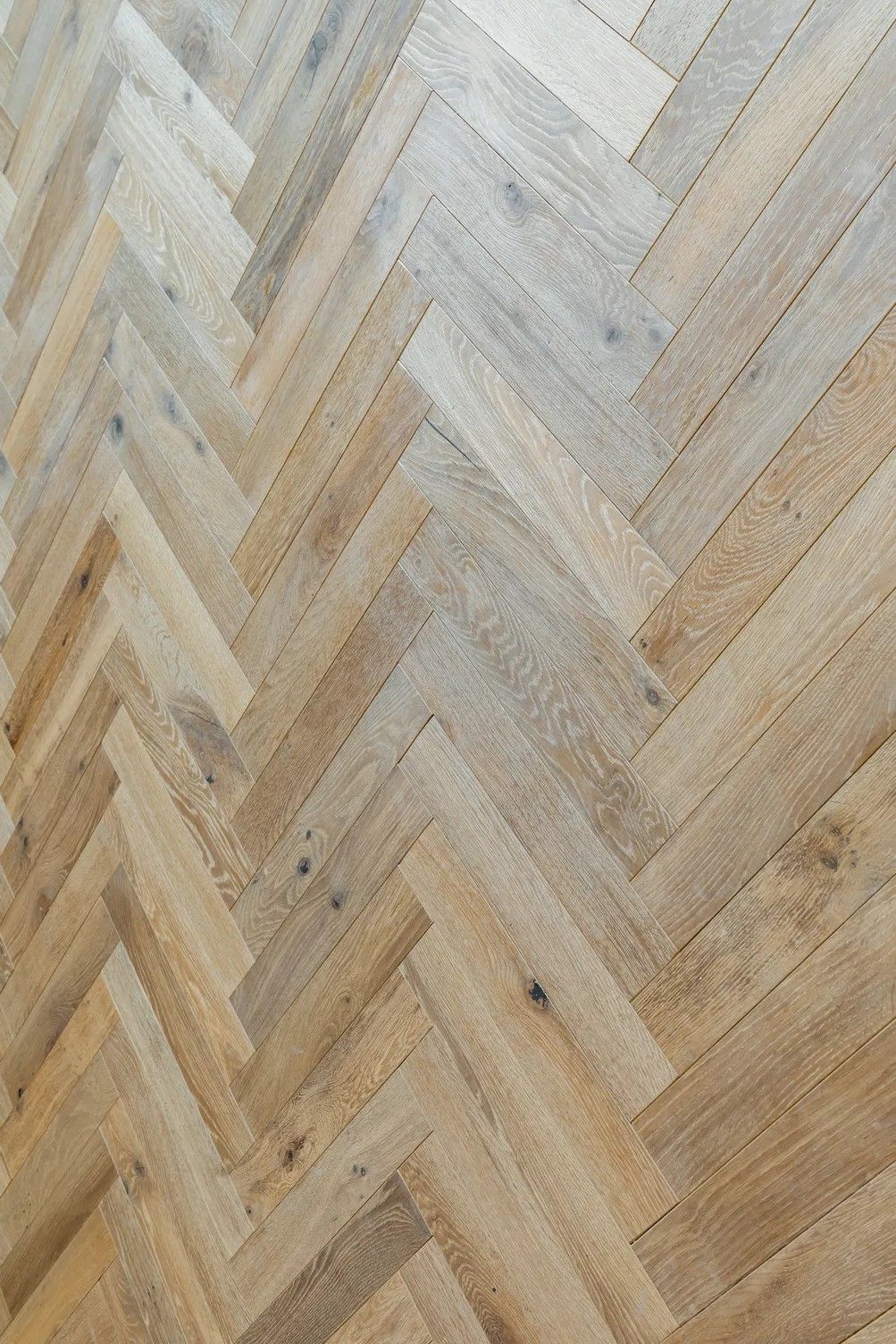 A close up of a wooden floor with a herringbone pattern.