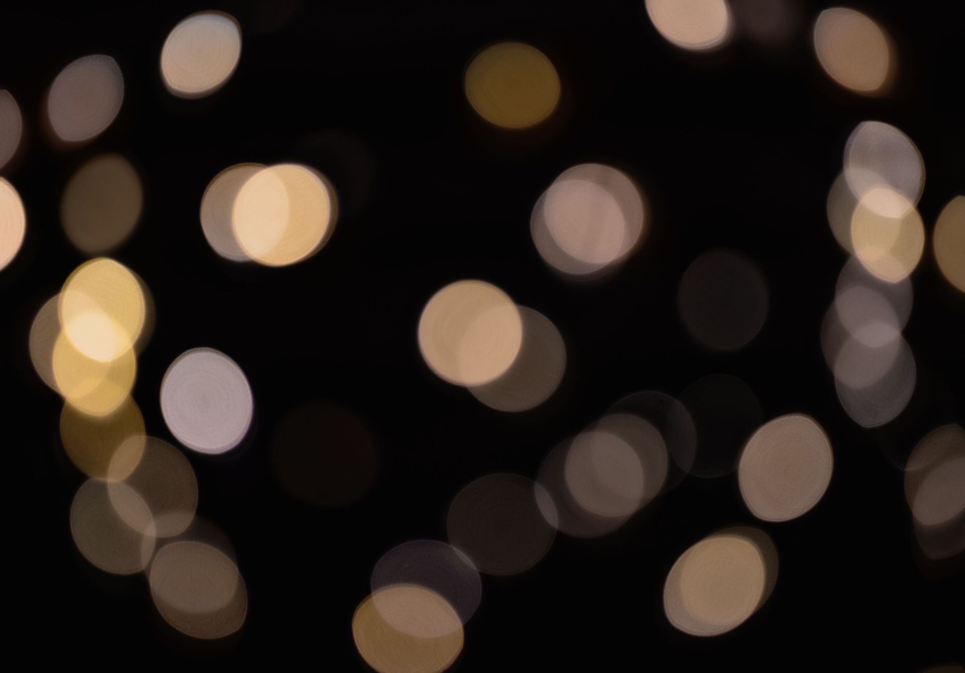 Des lumières douces, floues, blanc chaud et or se détachent sur un fond noir.