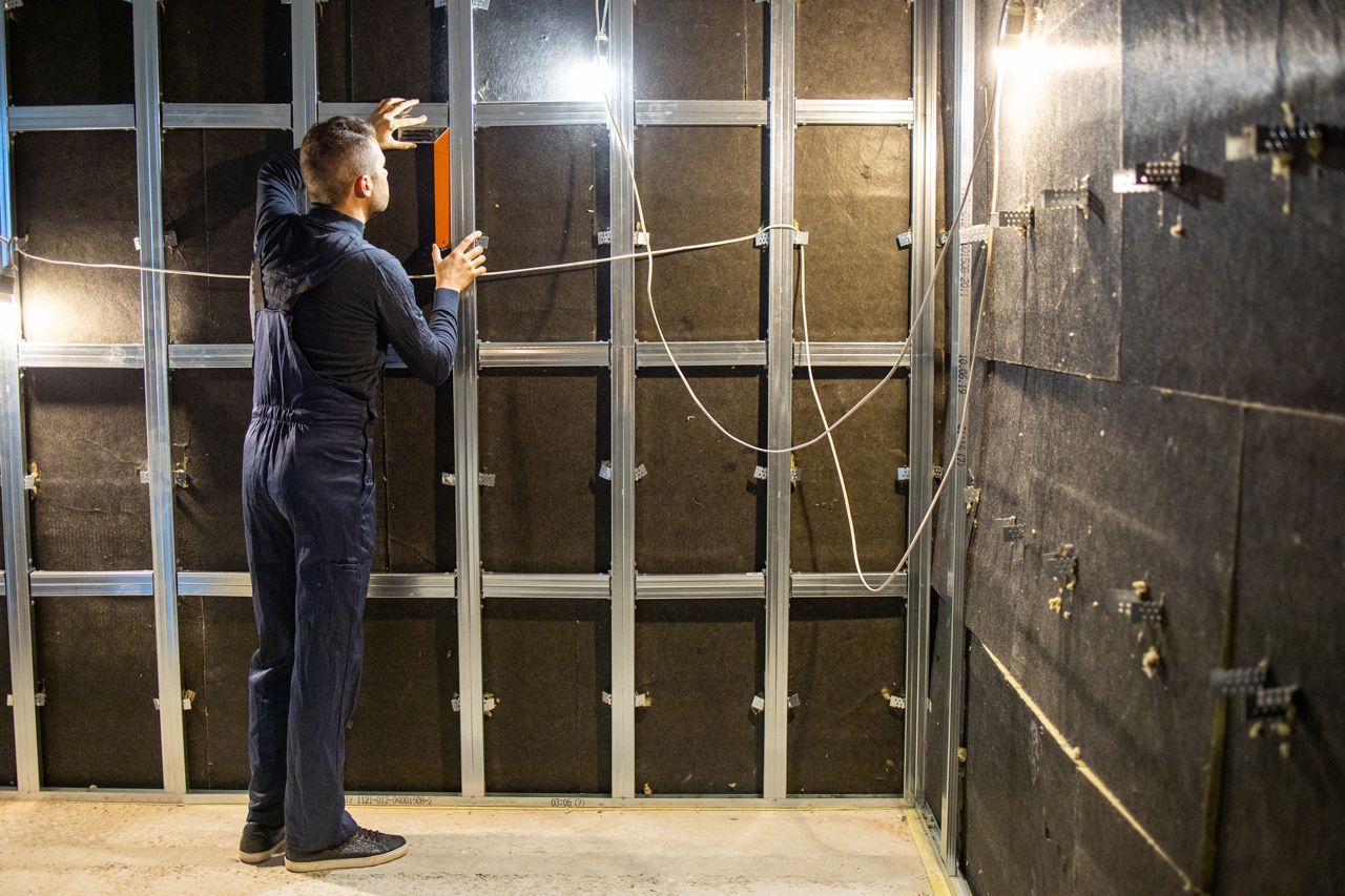 A man is standing in a room with a light on the wall.