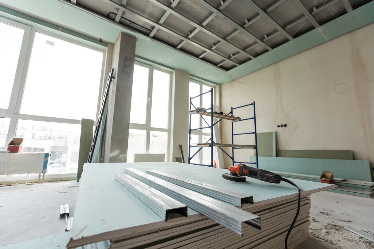 A room under construction with a stack of drywall and a drill.