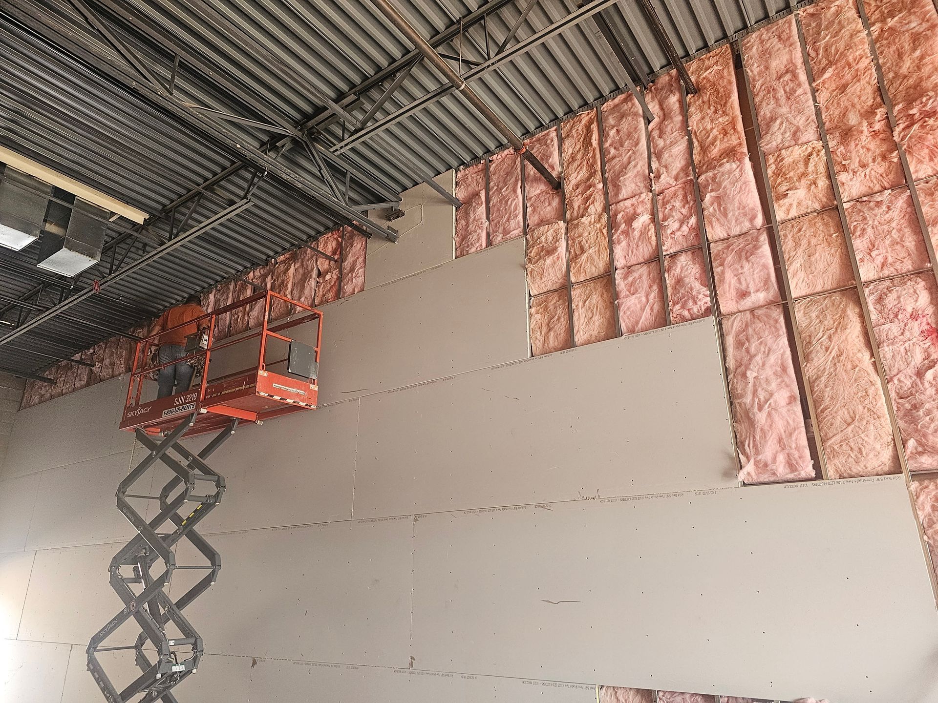 A person is working on a wall with a scissor lift.