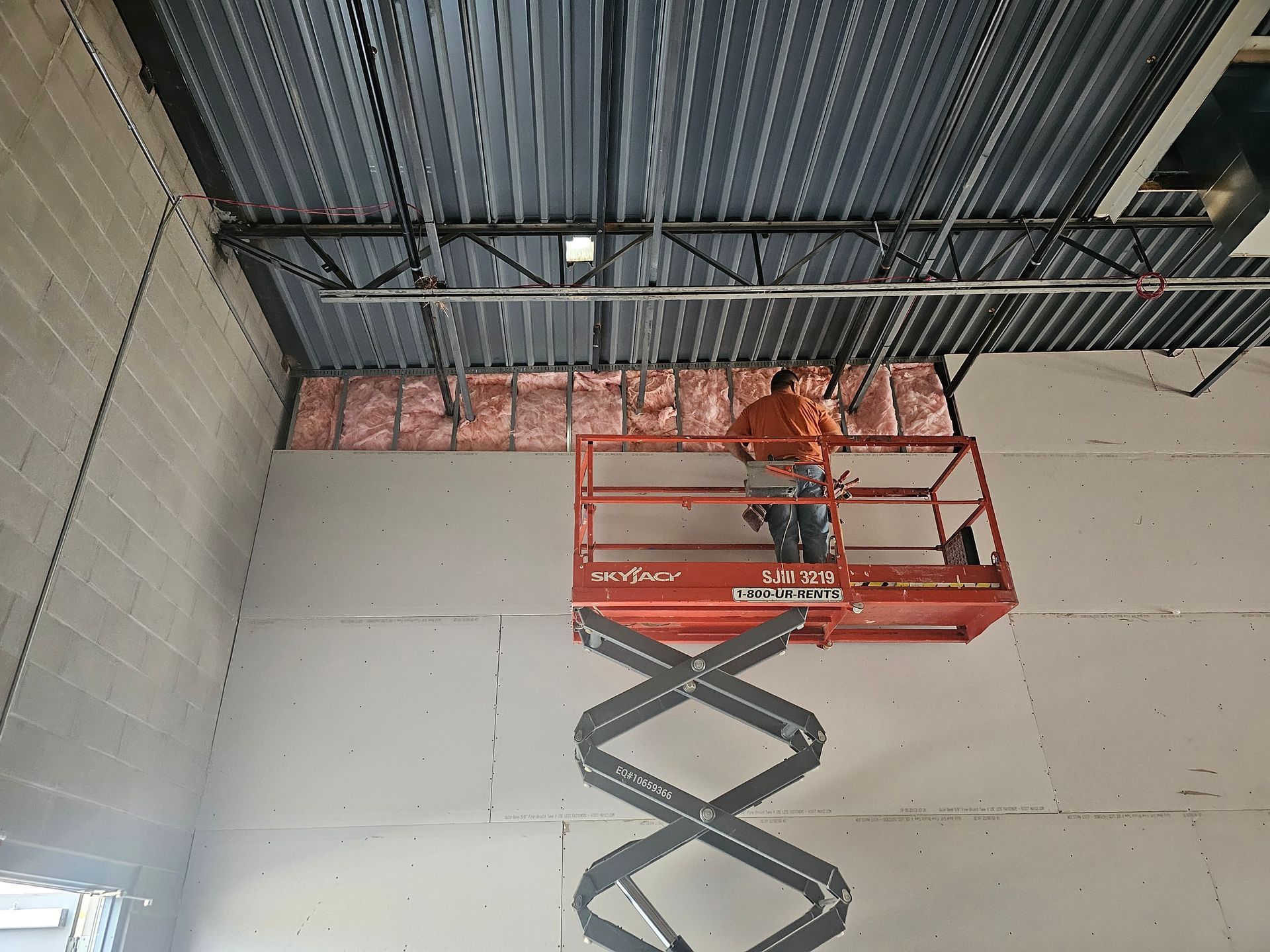 A man is standing on a scissor lift in a building.