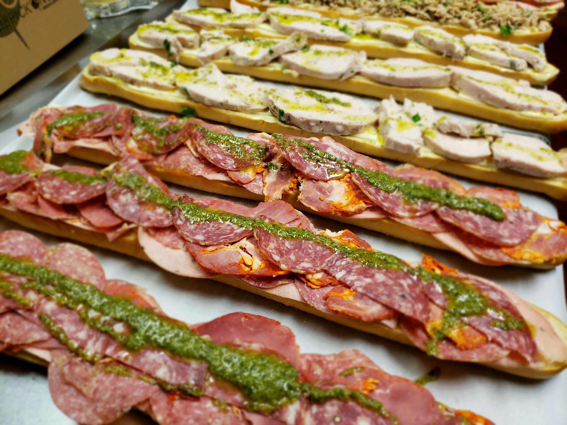 Long Italian sandwiches layered with meat and pesto, ready to serve.