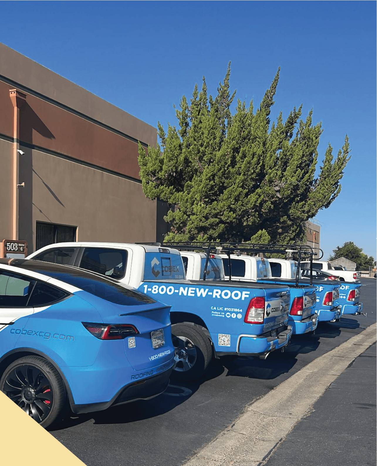 A row of blue cars and trucks parked in front of a building