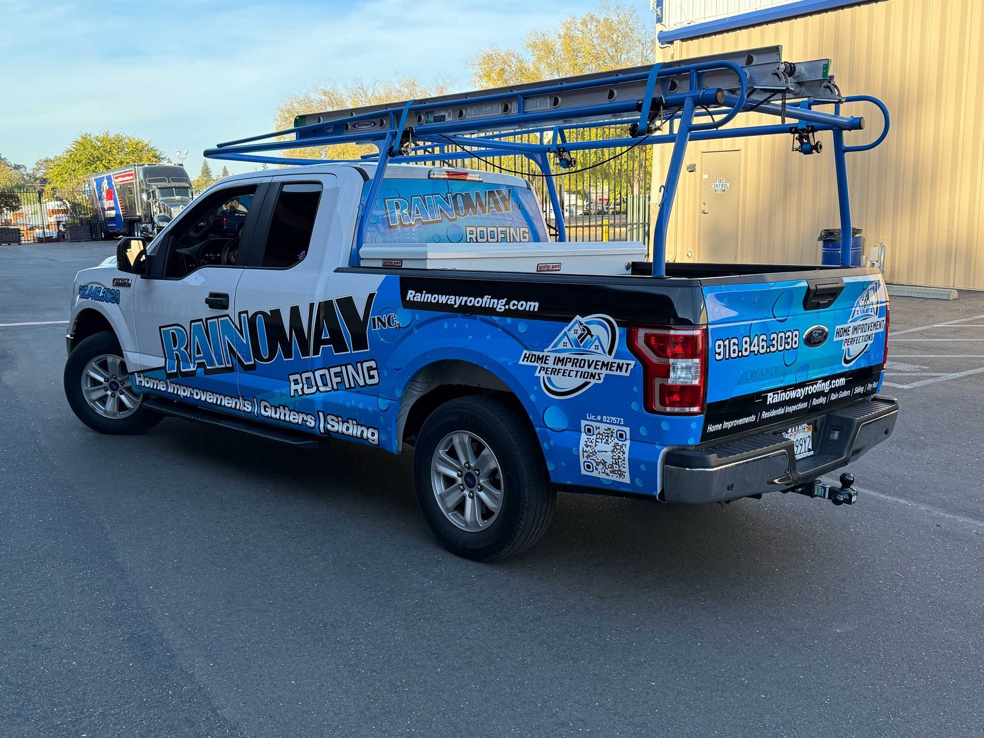 Blue utility pickup truck with ladder rack parked on a street in daylight