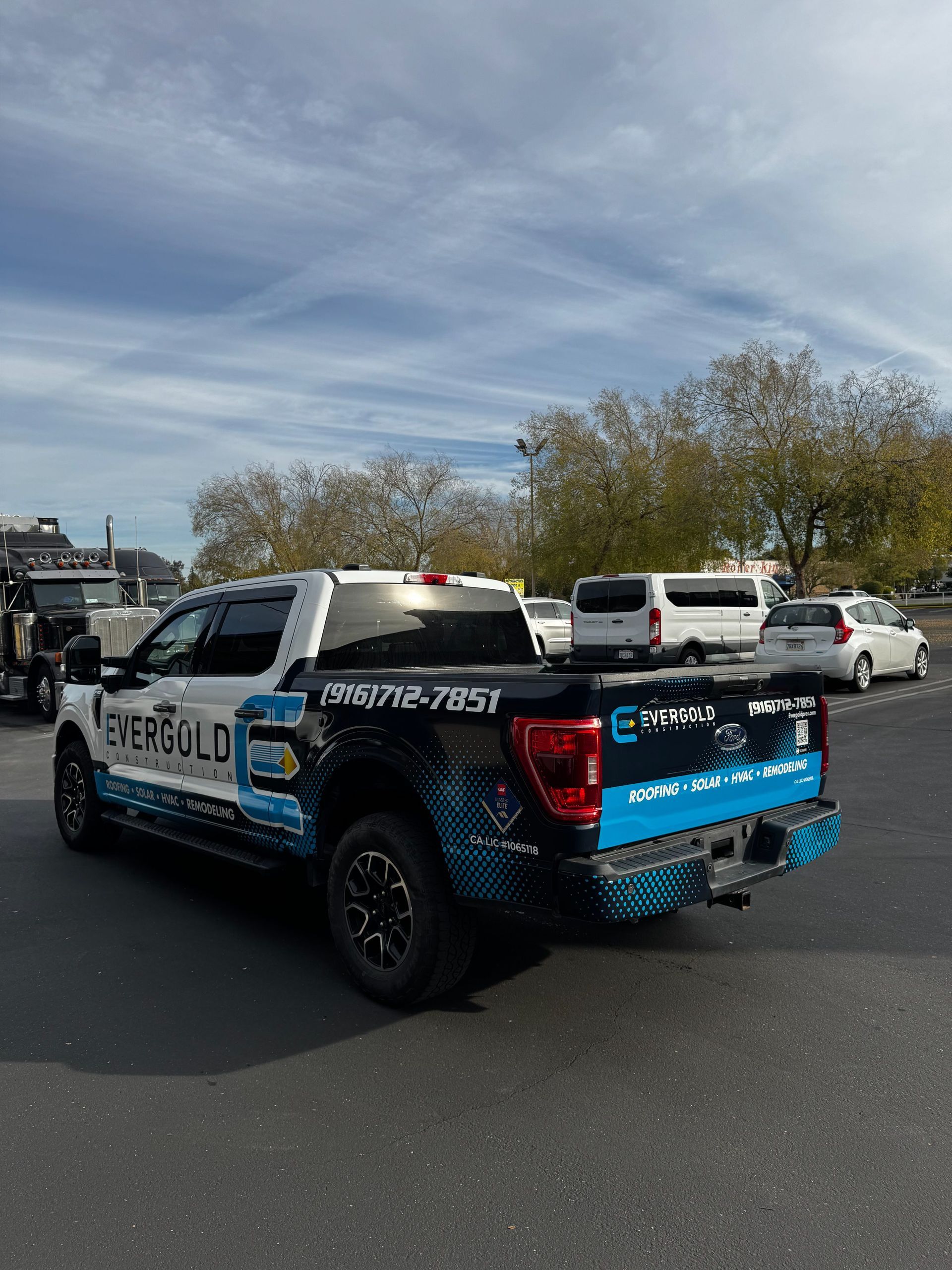 Police pickup truck with blue-and-black wrap parked in a lot under a cloudy sky