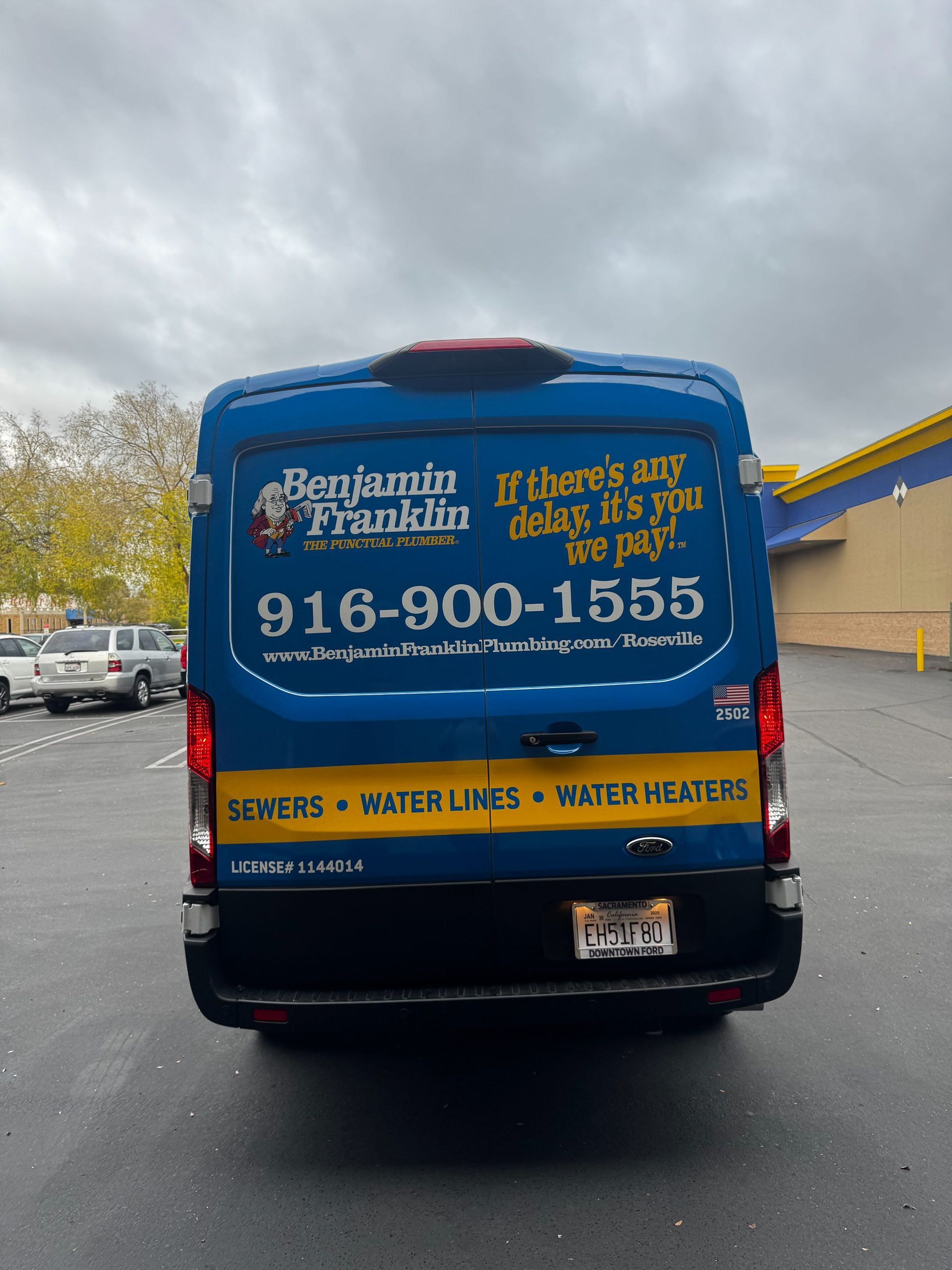 Blue service van with 916-900-1555 and plumbing/septic/water cleanup text in a parking lot