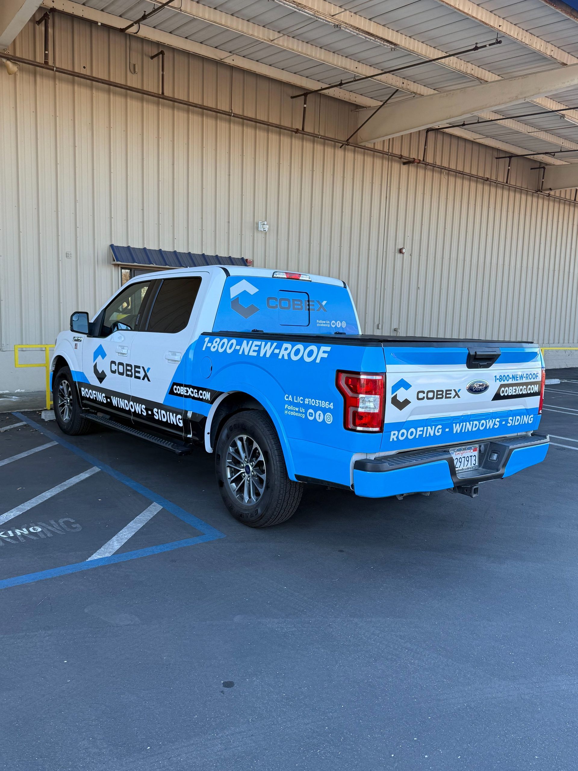 Blue and white Chevy pickup with sponsor decals parked under a metal awning