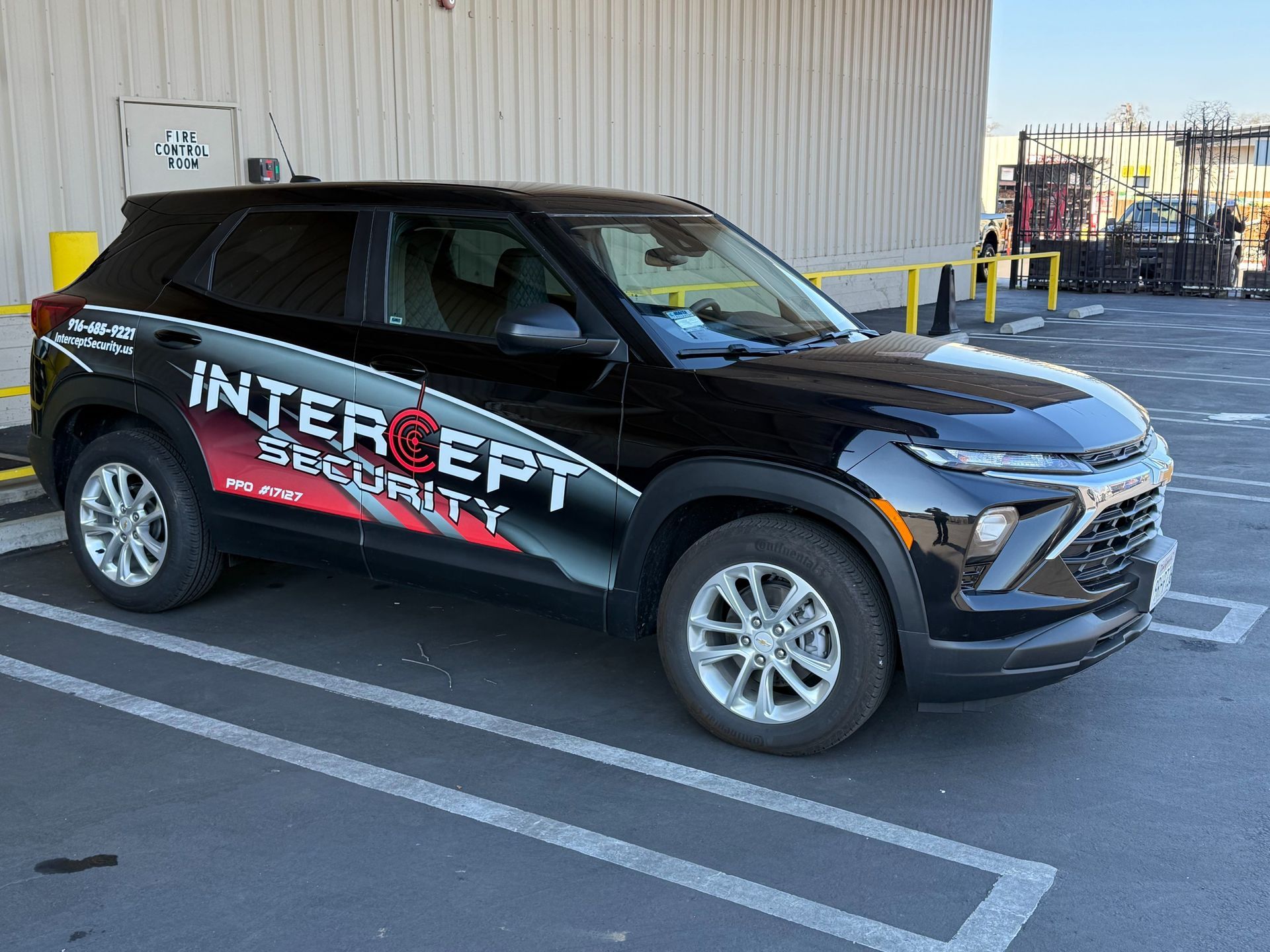 Black Intercept Security SUV parked in a lot beside a warehouse.