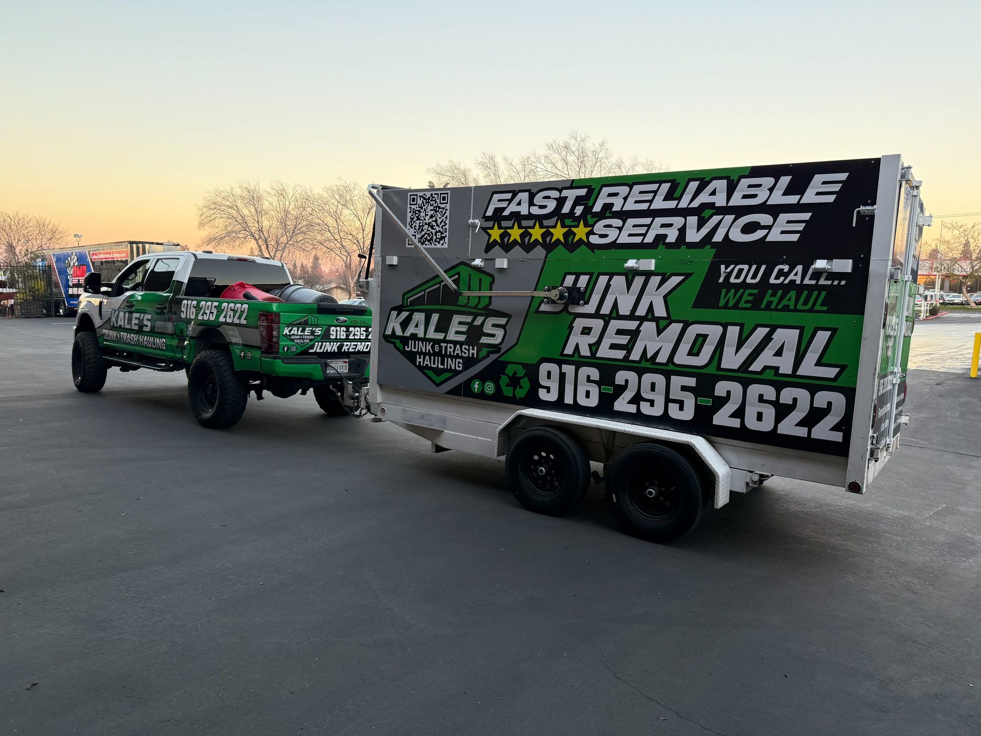 Green tow truck with “INK REMOVAL” trailer parked outdoors at dusk, advertising fast reliable service.