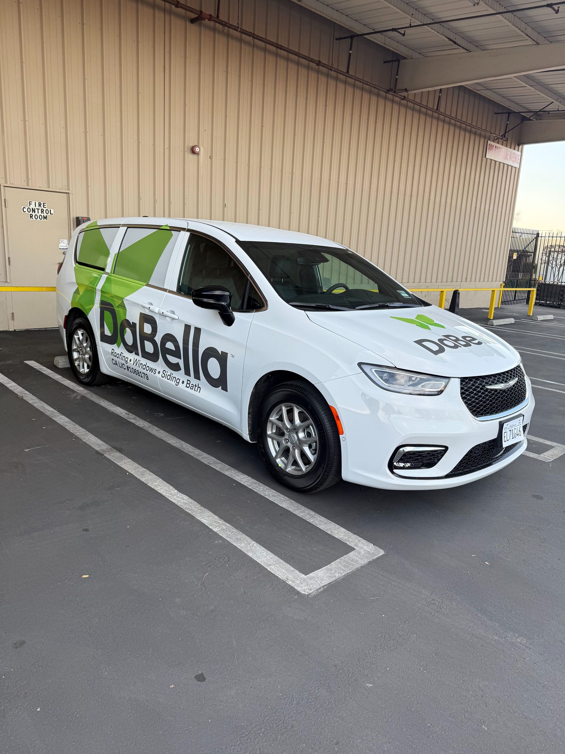 White delivery car with “BoBella” logo parked in a marked lot beside a beige wall.
