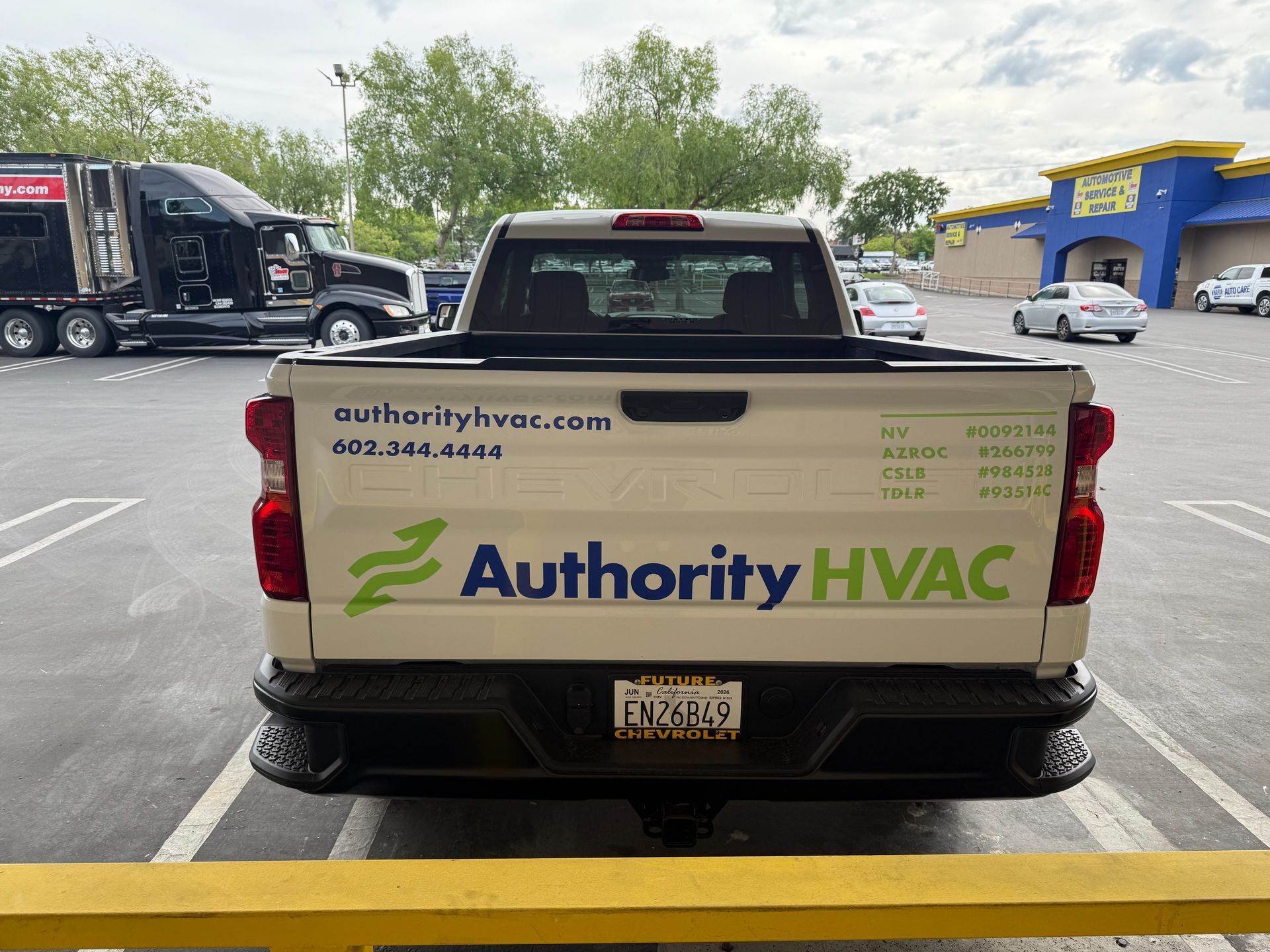 White Authority HVAC pickup truck parked in a lot, rear view with company logo and website on the tailgate