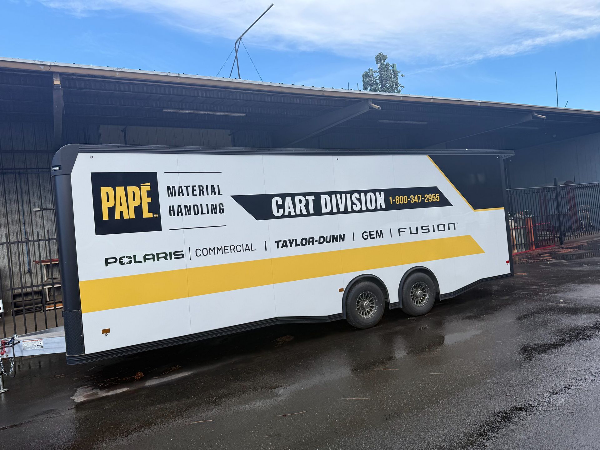 White card-dividing trailer with “PAPE” branding parked beside a building on a wet lot.