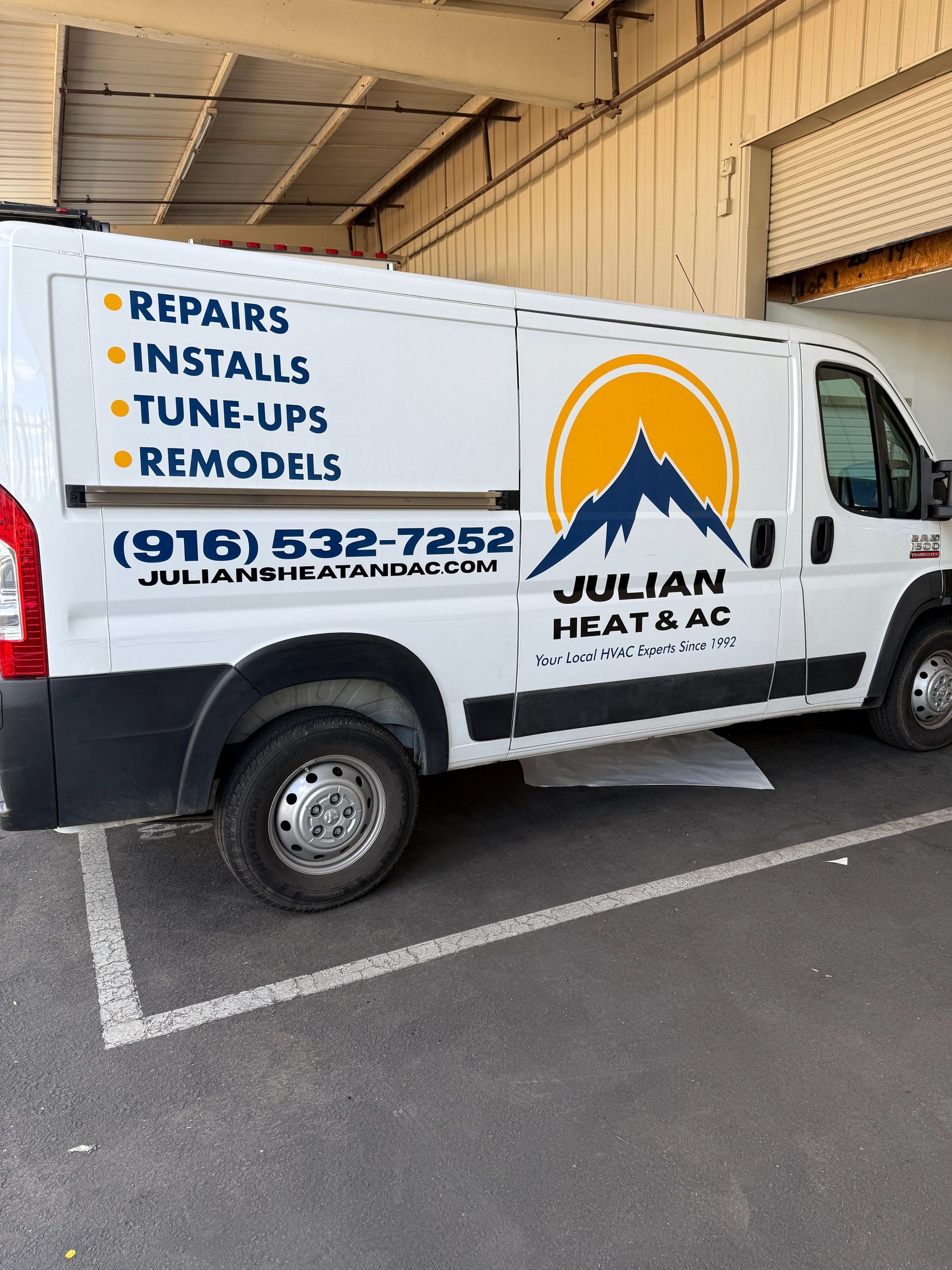 White Julian Heat & AC service van parked outdoors with repair, install, tune-up, and remodel text on the side