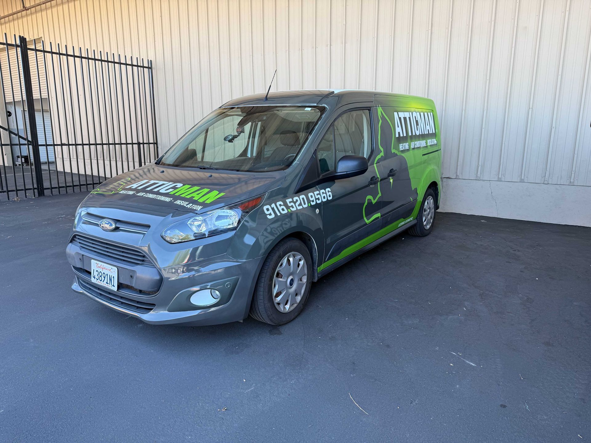 Gray and green branded van parked outside a building, front-left view