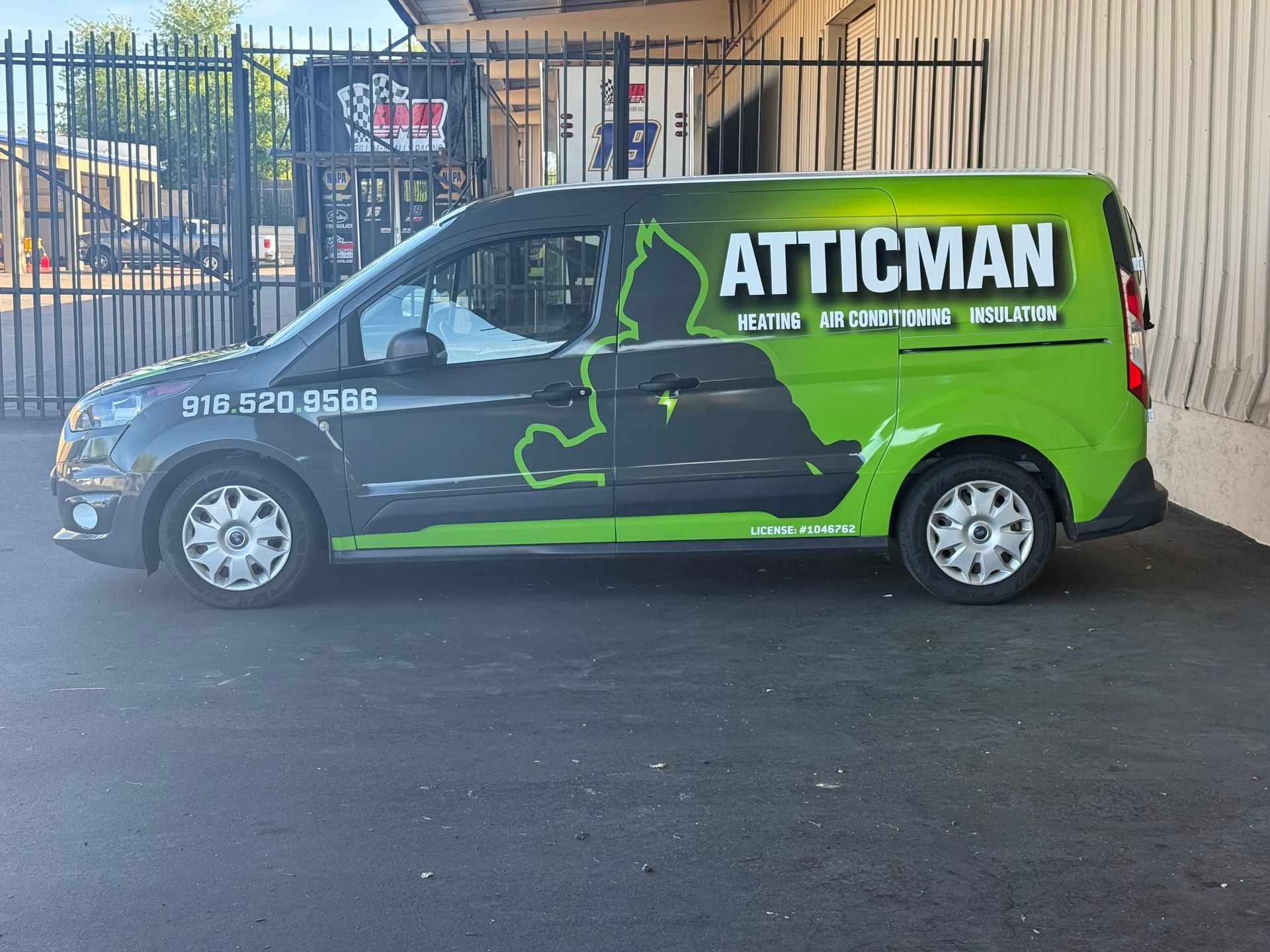 Green and black ATTICMAN service van parked outdoors under a covered area